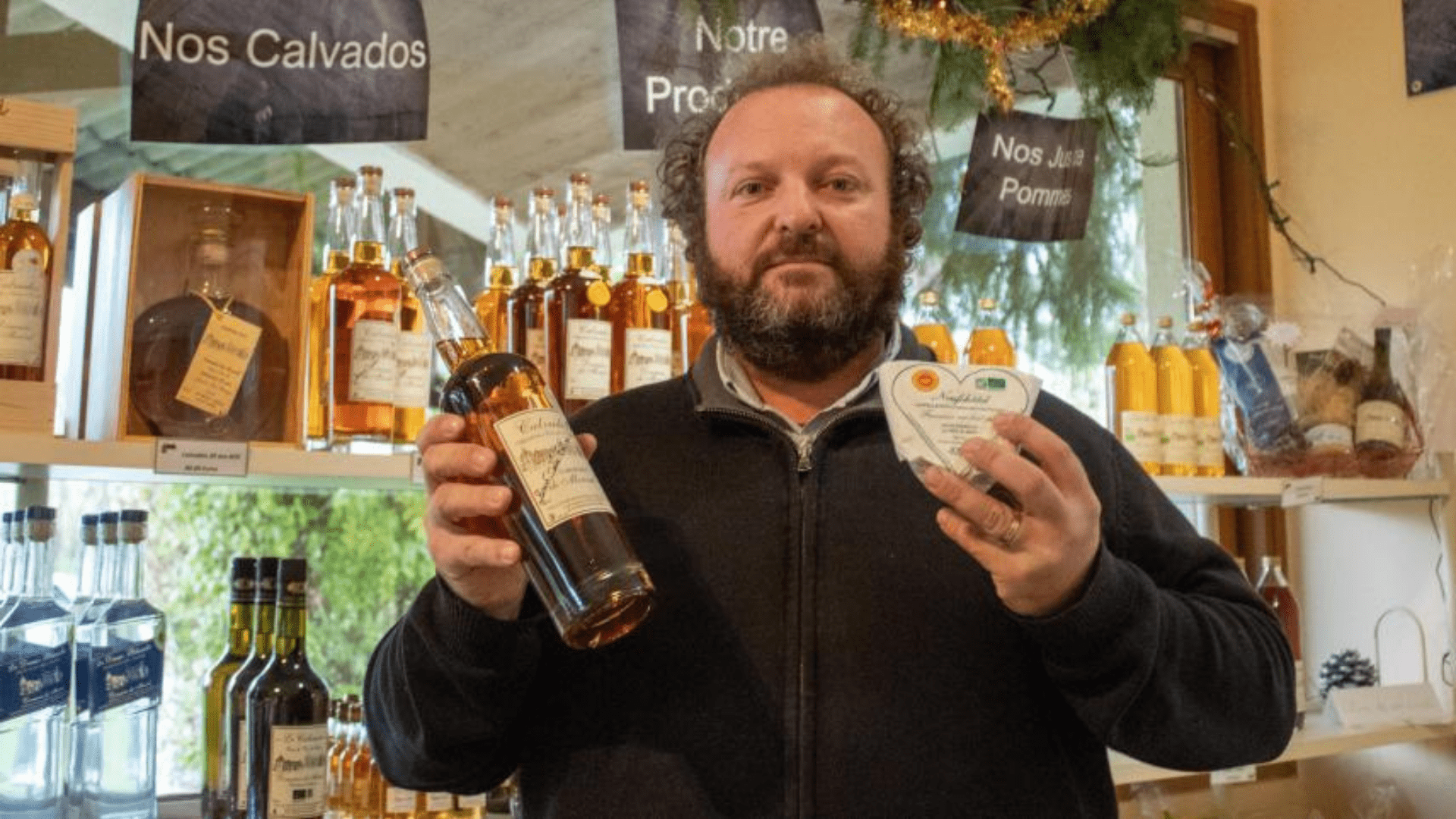 Bertrand Cailly tenant deux bouteilles de Calvados fabriqué au domaine de Merval.